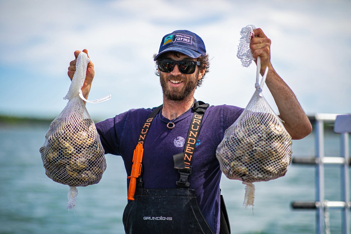 Eric Oransky, founding partner, Maine Ocean Farms, holding up two filled beechwood oyster harvest bags. Credit: Ocean Farms Supply