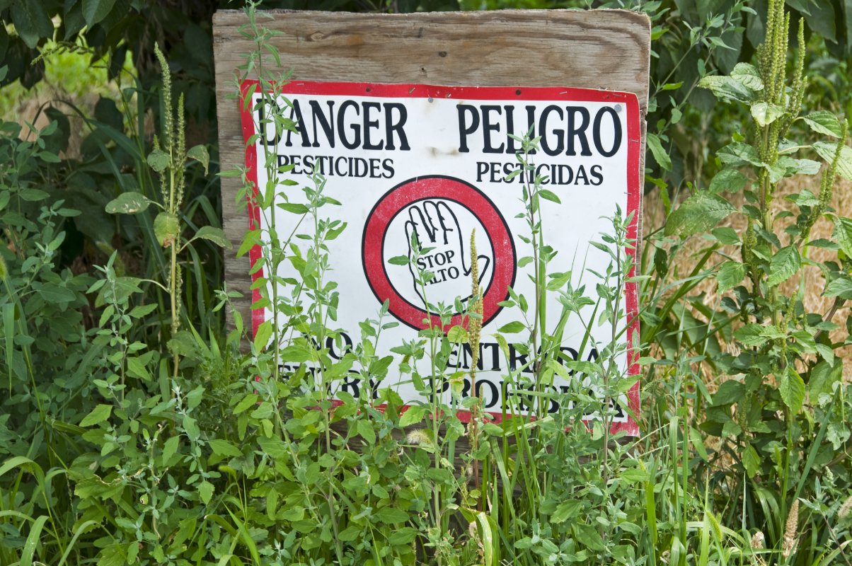 a sign warning in english and spanish about pesticides being applied