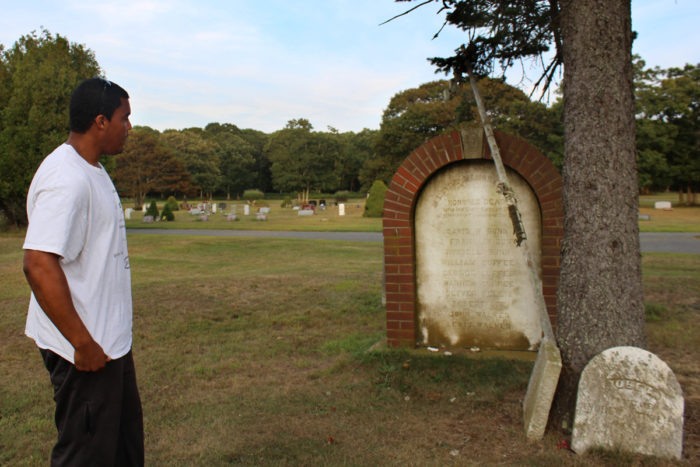 Shinnecock tribe member Shane Weeks visits the Shinnecock cemetery, looking at a memorial for the 10 Shinnecock men who died in the 1876 shipwreck of the Circassian off the coast of Mecox Bay in Bridgehampton. (Photo by Alexandra Talty)