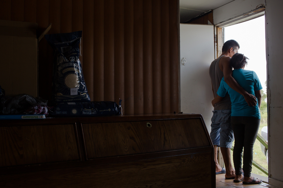 A farmworker couple, Nelson and Silvia* from Guatemala, surveys the flooding outside of their North Carolina trailer home after Hurricane Florence. (Photo by Justin Cook.)