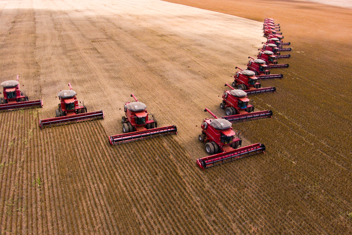 tractors driving across a large consolidated farm field