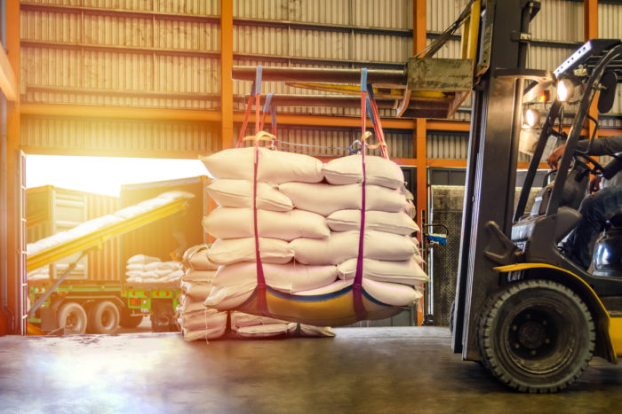 forklift loading large bags of sugar for transportation in a warehouse