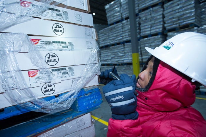 A USDA Food Safety Inspection Service inspector examines a shipment imported frozen meat at the Port of New Orleans. (USDA photo by Anson Eaglin.)