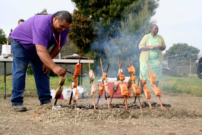 Glenn Moore, Hoopa/Yurok Cultural Practitioner arranges salmon on skewers during a traditional baking demonstration. (Photo CC-licensed by the U.S. Forest Service)