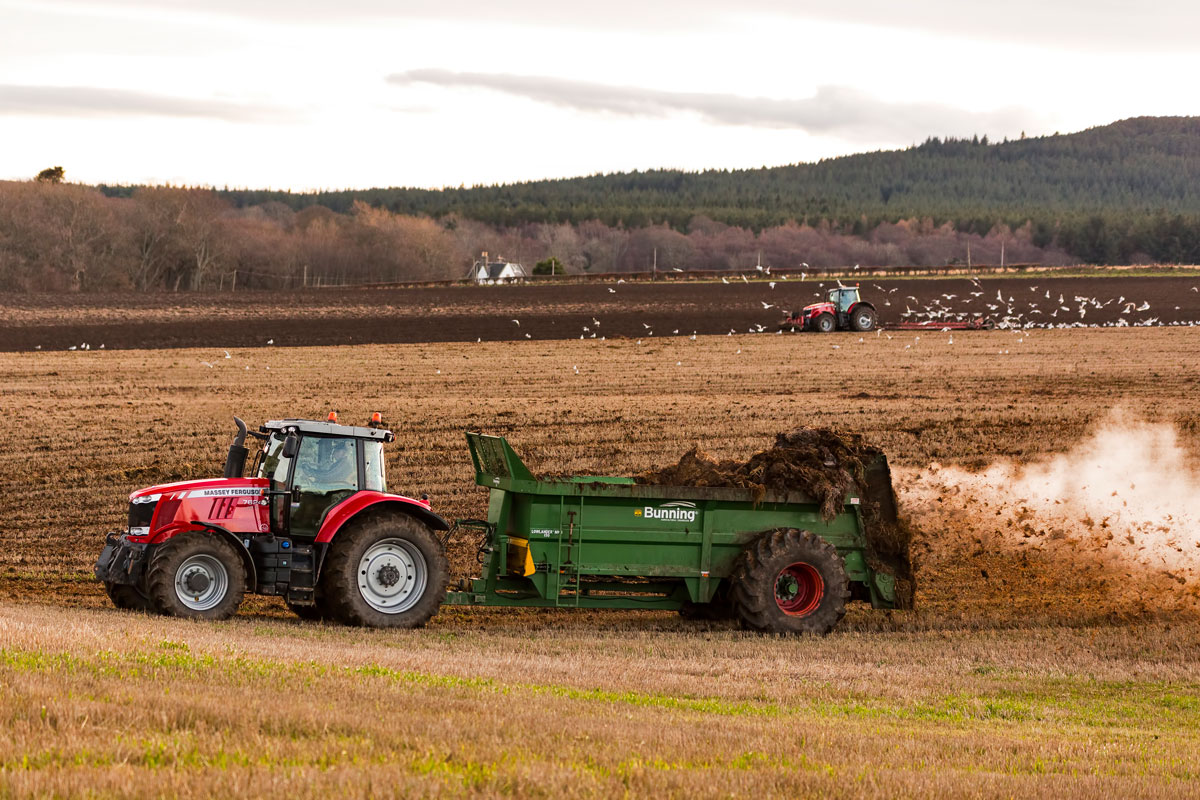 tractor spreading biosolids as fertilizer over farmland