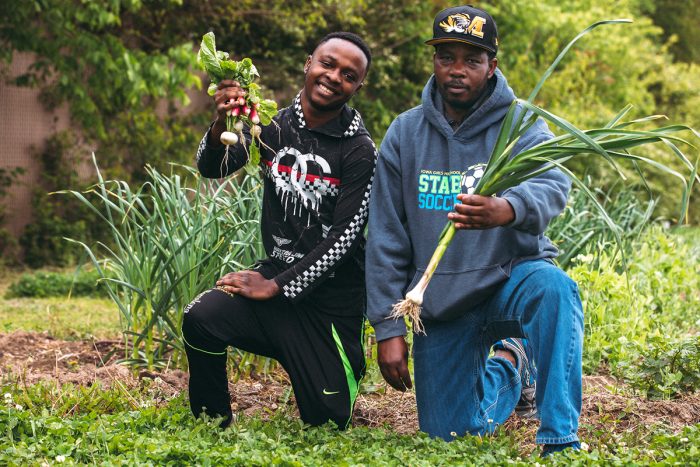 Two of New Roots' farmers show off some of their harvest. (Photo credit: IM Photography)