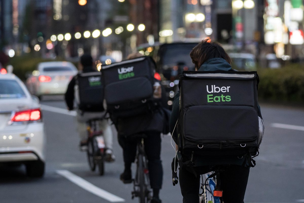 Uber Eats food delivery app riders lining up in the street to deliver food from restaurants