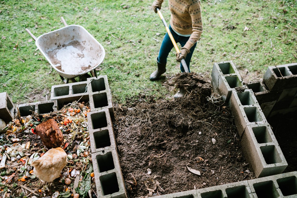 farmer shoveling compost to spread on their organic farm.