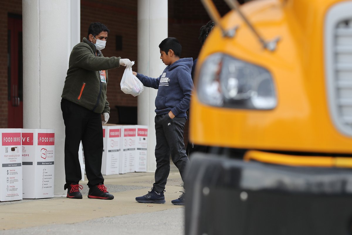 Montgomery County Public Schools Special Needs Bus Attendant Bhavin Savla helps distribute bags of food donated by Manna Food Center at Quince Orchard High School as part of a program to feed children while schools are closed due to the coronavirus March 20, 2020 in Gaithersburg, Maryland. Millions of children across the country rely on meals they get at school, which are closed in an attempt to suppress transmission of the COVID-19 virus. (Photo by Chip Somodevilla/Getty Images)