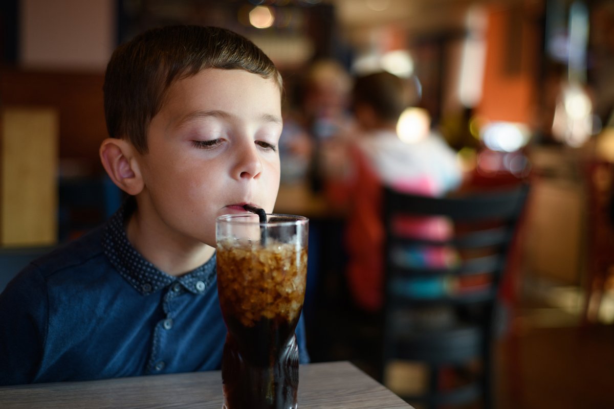 child drinking a large soda