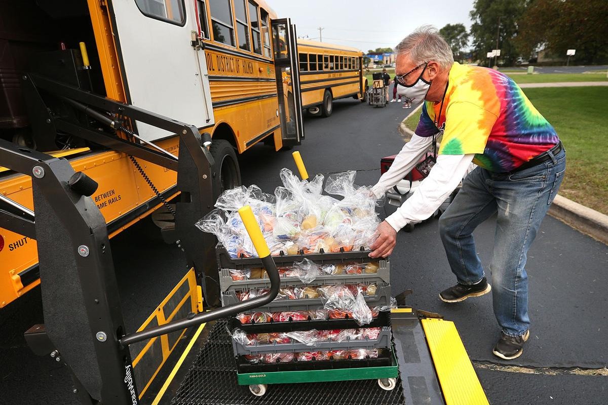 A Holmen School District transportation employee loads lunches onto a school bus before helping deliver them throughout the community.