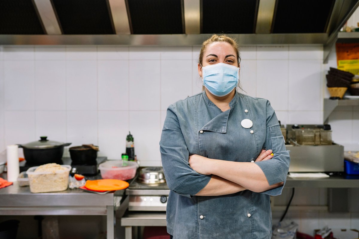 A woman chef stands in her new york city restaurant wearing a mask during the covid pandemic