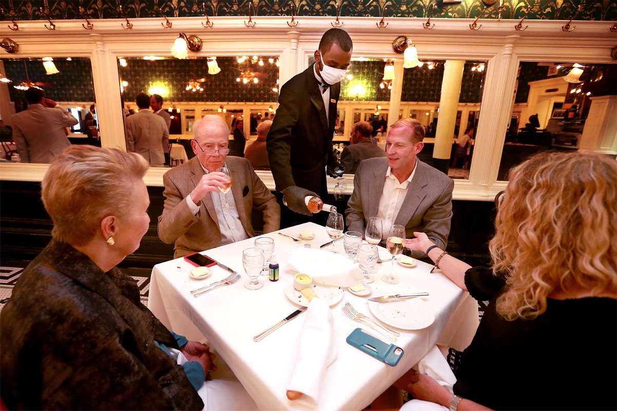 A waiter pours wine during dinner at Galatoire's Restaurant on May 22, 2020 in New Orleans, Louisiana. (Photo by Sean Gardner/Getty Images)