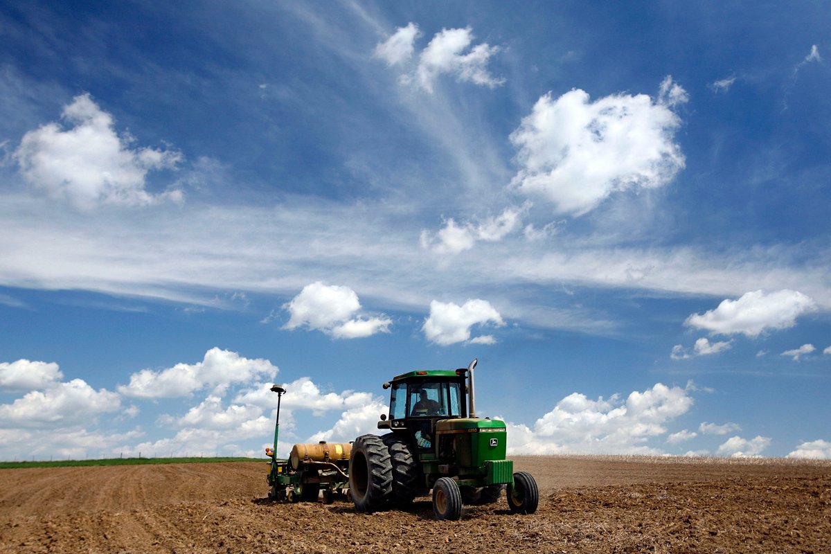 farmer driving his john deere tractor around the farm, hoping it doesn't break because at the time of this photo he didn't have right to repair his farm equipment