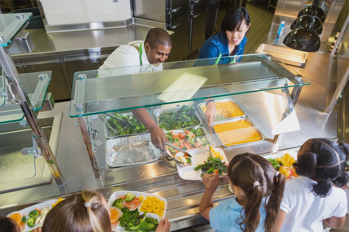 cafeteria workers serve farm to school produce to students to improve their nutrition and support local farmers