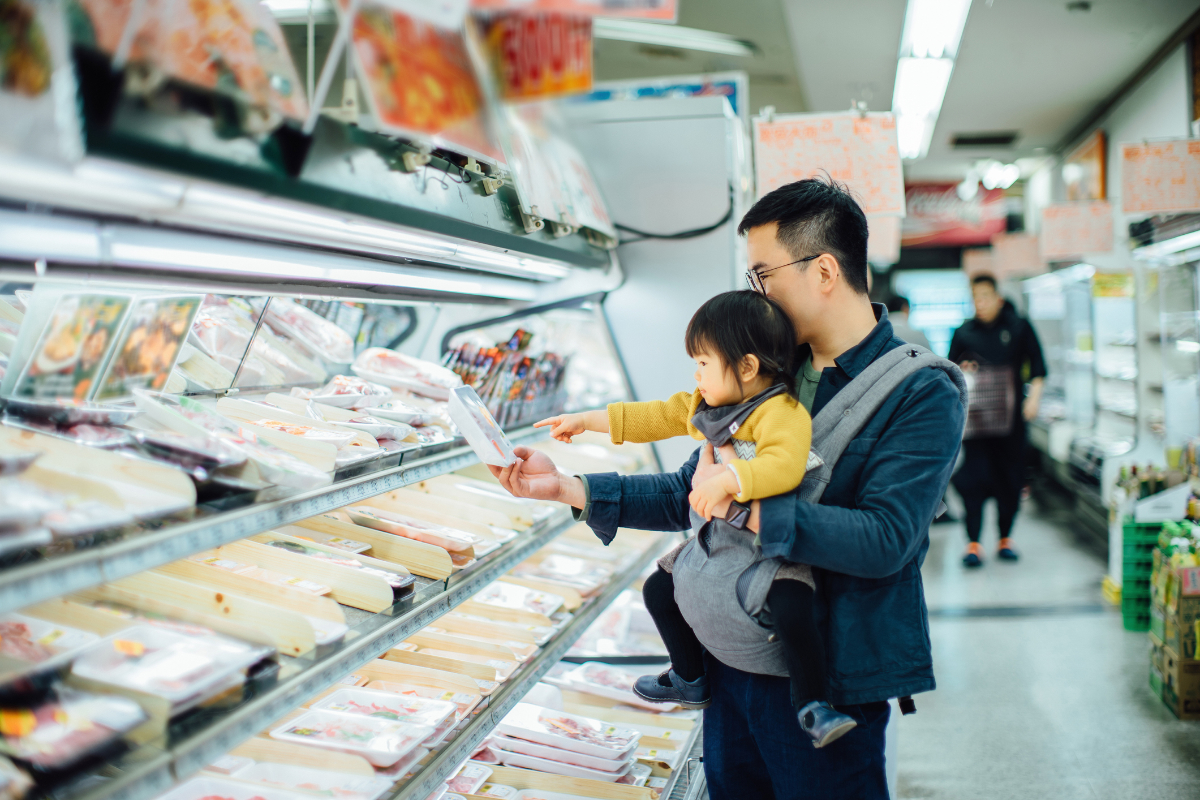 Young Asian father grocery shopping with cute little daughter in supermarket, they are shopping for fresh meat