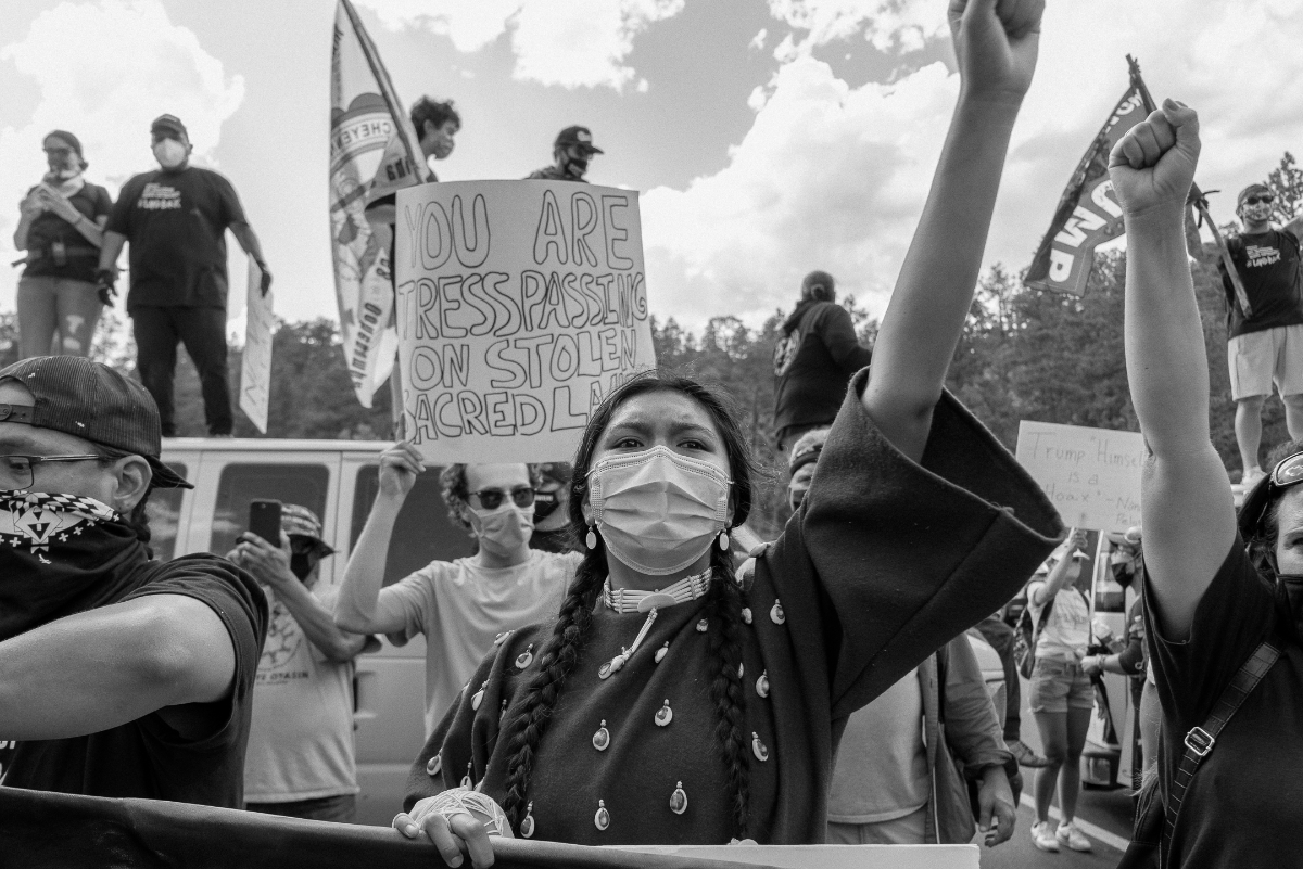 Black and white photo from a Landback protest in the Black Hills in July 2020. (Photo credit: Arlo Iron Cloud, NDN Collective)