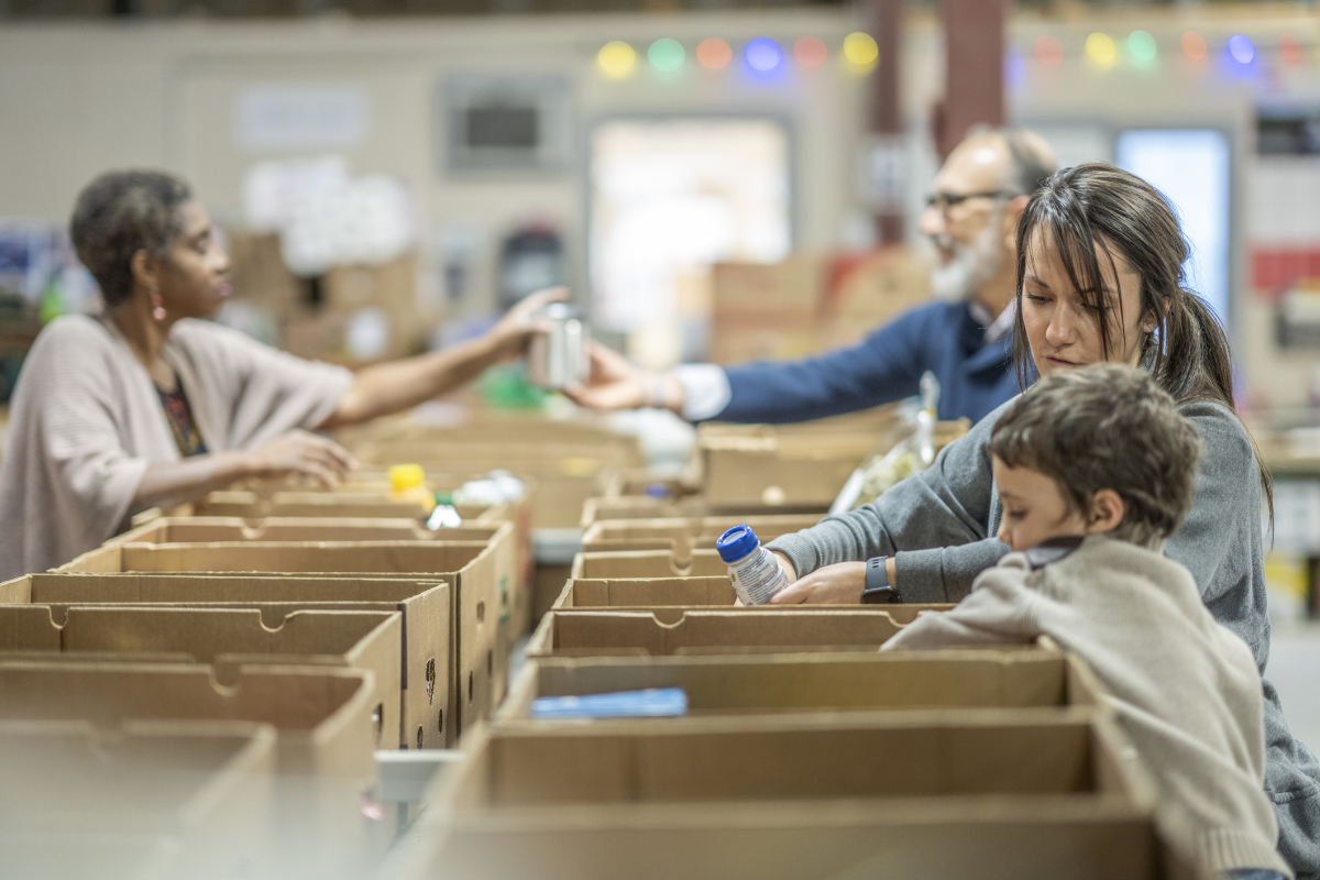 Small group of people donating their time by working in a warehouse to organize and distribute non-perishable goods to families and people in need.