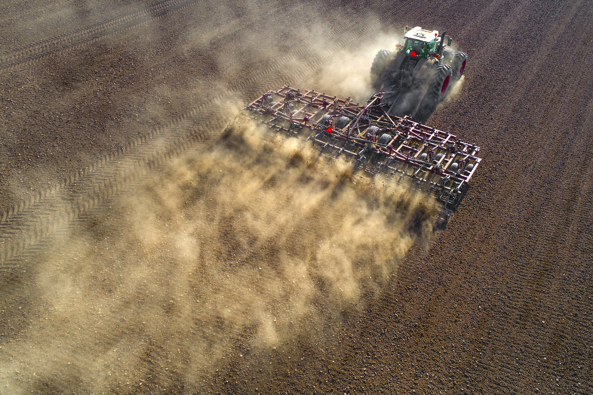 Big farm tractor tilling dusty Springtime fields