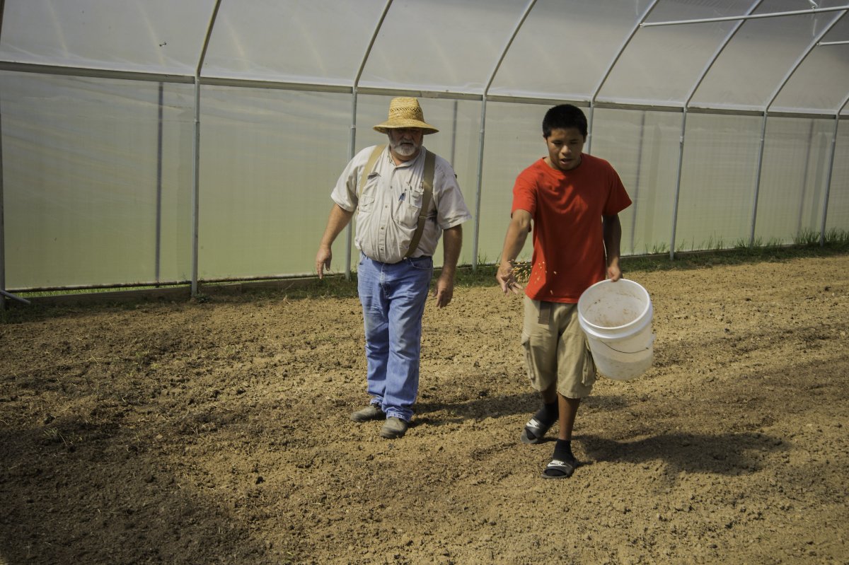 Eldrige Hoy, left, and Bryson Sam, members of the Choctaw Nation, seed a high tunnel with Iron Clay peas as a cover crop to improve soil quality. (USDA photo by Bob Nichols)