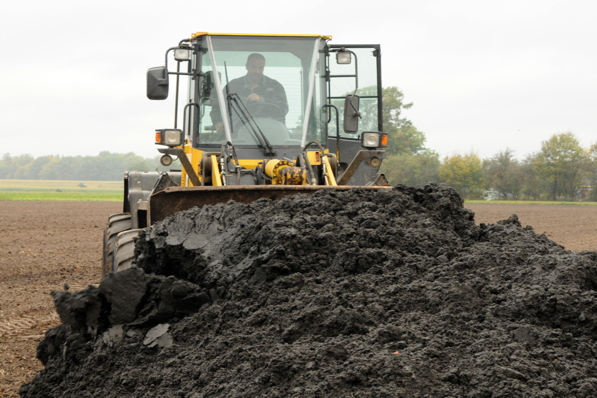 A farm tractor loads solid sewage sludge for distributing in the field. (Photo CC-licensed by the Sustainable Sanitation Alliance on Flickr)