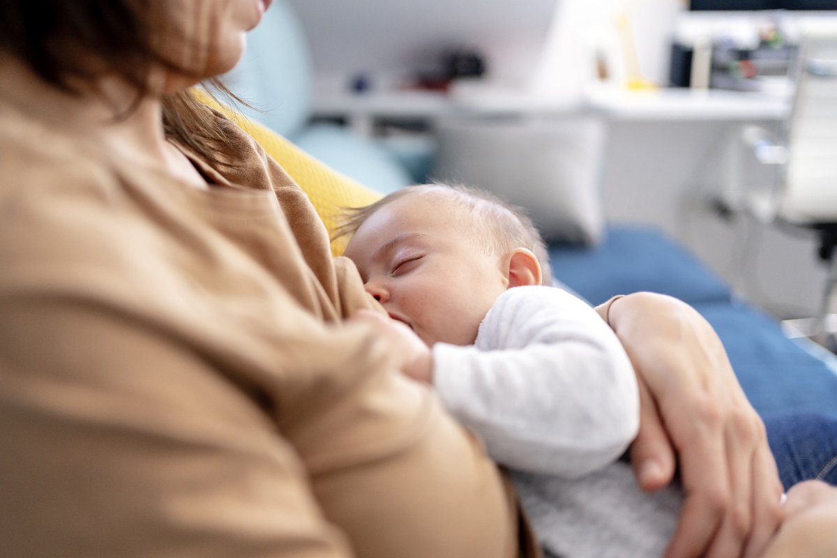 Mother breastfeeding her son at home