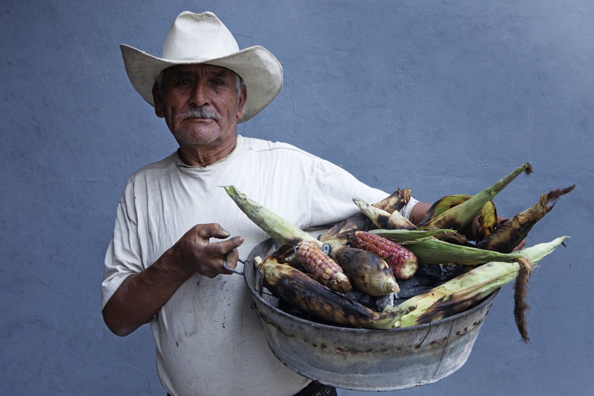 A Mexican farmer holds a basket of corn to sell.