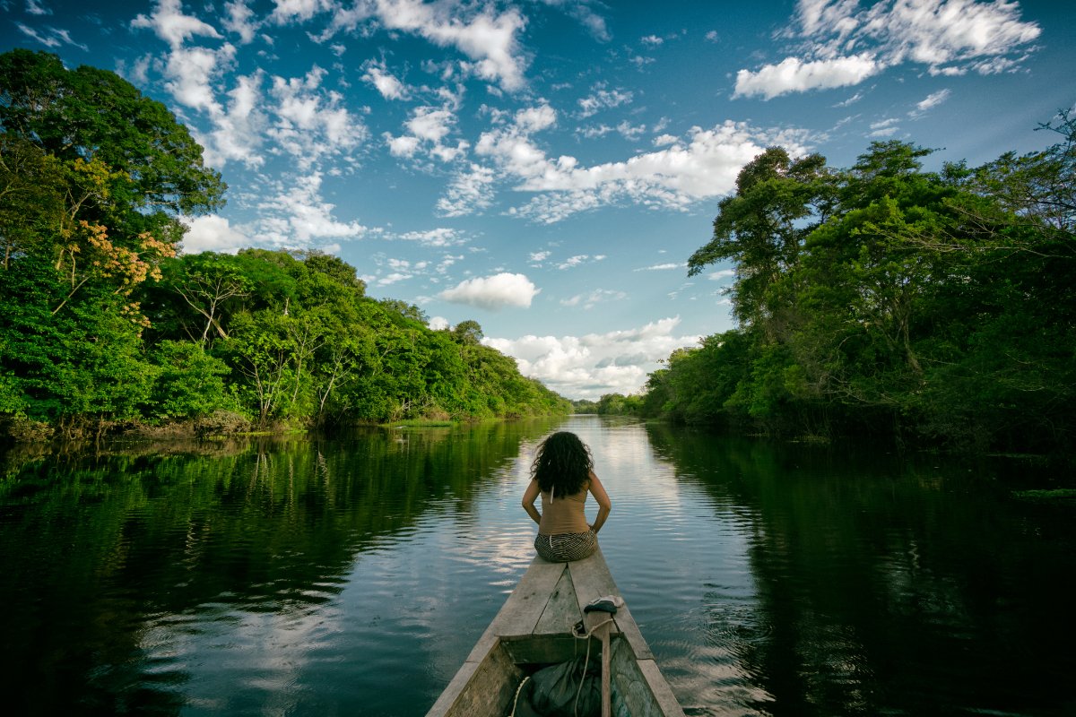 Sailing in a wooden boat on the Amazon river in Peru. An indigenous girl sitting on the front of the boat whilst sailing down the river.