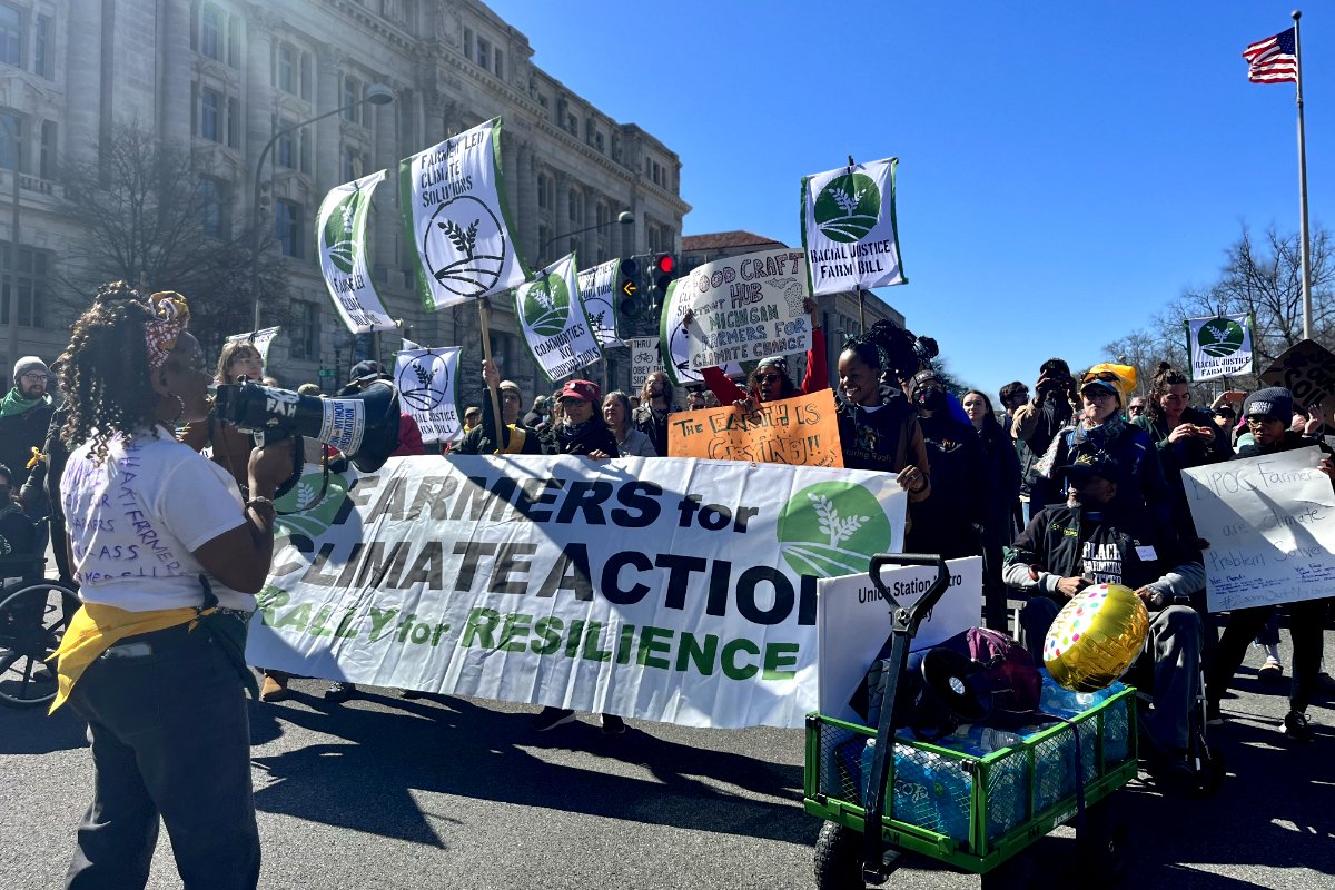 The Rally for Resilience marches to the U.S. Capitol building. Signs at the front read 