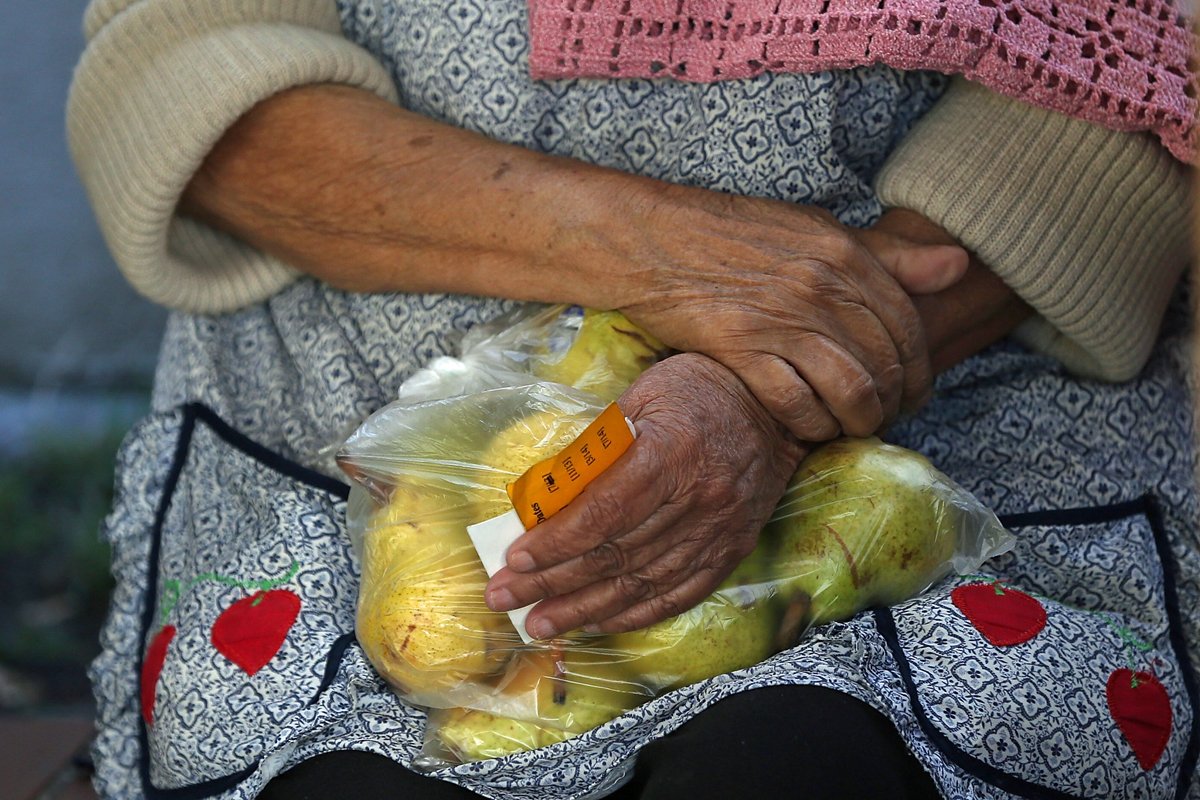 A woman holds a bag of pears as she waits in line to receive free food at the Richmond Emergency Food Bank. (Photo by Justin Sullivan/Getty Images)