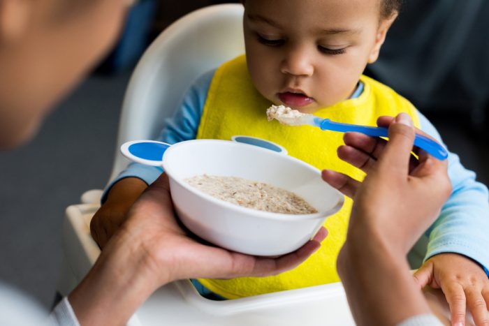 a young parent feeds an infant food that they bought using their wic benefit