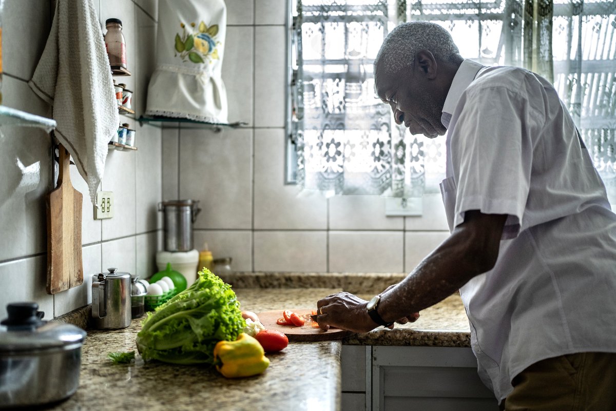 a Black senior cooks food in his kitchen to fight food insecurity.