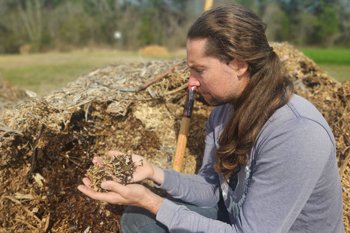 Timothy Robb inspects a pile of decomposing wood chips. (Photo credit: Grey Moran)