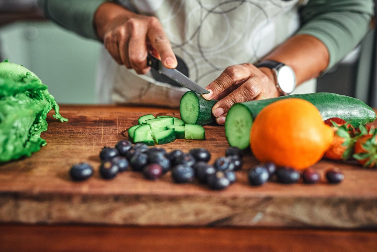 a home cook chopping vegetables on a cutting board for a salad or other healthy meal