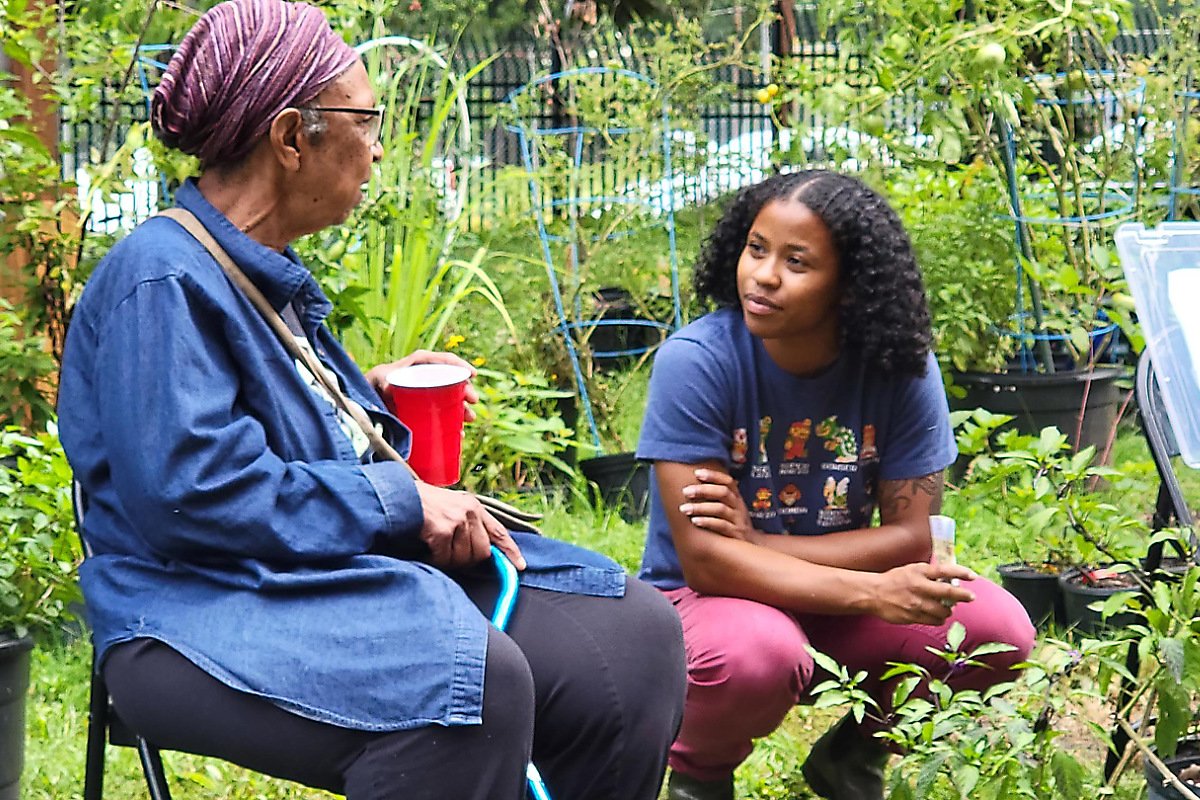 Ira Wallace (left) and Sariyah Benoit sit together in Spelman College’s Victory Garden. (Photo credit: Heirloom Gardens Project)