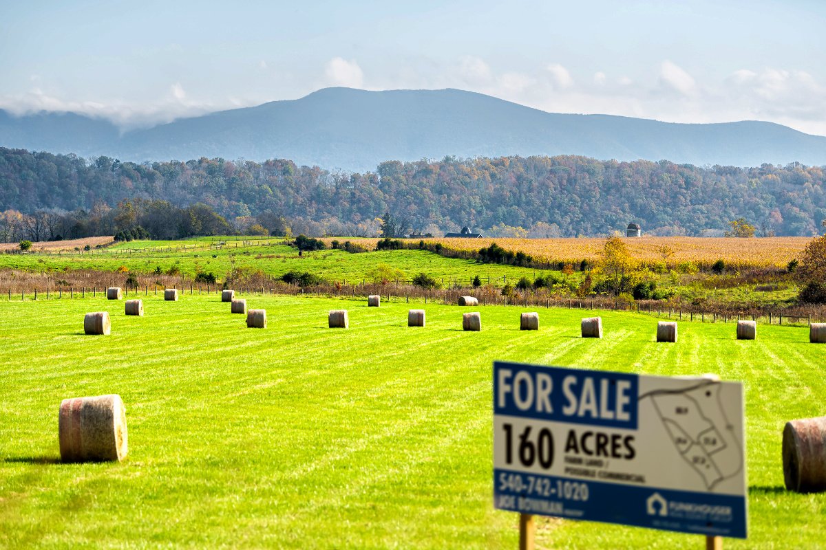 Farmland for sale, a photo of hay bales in a field listed for sale.